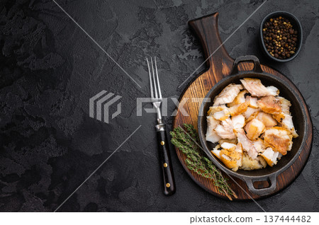 Fried white fish pieces served in small skillet on rustic wooden board with herbs and spices. 137444482