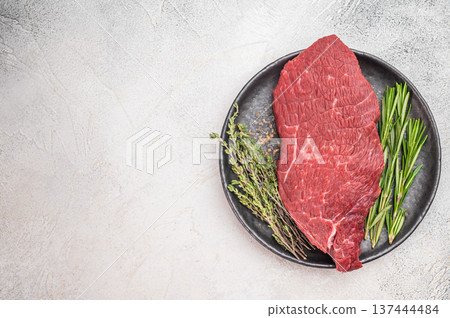 Fresh raw beef sirloin tip knuckle on dark ceramic plate. Lean butcher cut red meat prepared for cooking on light background. Fresh raw beef sirloin tip knuckle on dark ceramic plate. Lean butcher cut red meat prepared for cooking on light background. 137444484