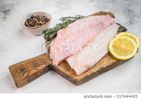 Ocean red perch fish fillets with lemon slices and pepper on cutting board. Fresh marine seafood ingredient for cooking.. Ocean red perch fish fillets with lemon slices and pepper on cutting board. Fresh marine seafood ingredient for cooking.. 137444485