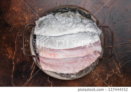 Top view of raw sea bass seabass fillets with thyme on rustic metal tray, clean culinary composition showing freshness, protein rich Mediterranean cuisine. Top view of raw sea bass seabass fillets with thyme on rustic metal tray, clean culinary composition showing freshness, protein rich Mediterranean cuisine. 137444552