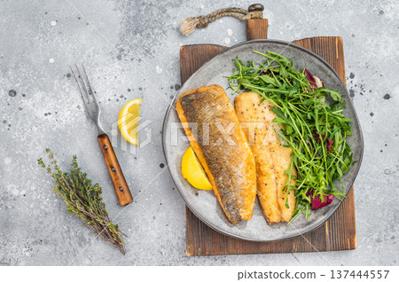 Crispy golden white fish zander fillet with herbs and lemon on plate, healthy seafood meal styled in modern overhead composition. 137444557