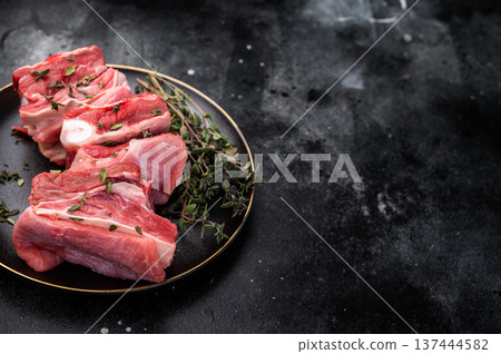 Raw mutton cut rib chops, fresh lamb meat with herbs for grilling. black background. top view Raw mutton cut rib chops, fresh lamb meat with herbs for grilling. black background. top view 137444582
