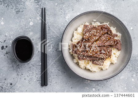 Delectable yakiniku feast, featuring a variety of marbled beef cuts and rice. A culinary journey that captures the essence of Japanese grilling traditions. grey background. top view Delectable yakiniku feast, featuring a variety of marbled beef cuts and rice. A culinary journey that captures the essence of Japanese grilling traditions. grey background. top view 137444601
