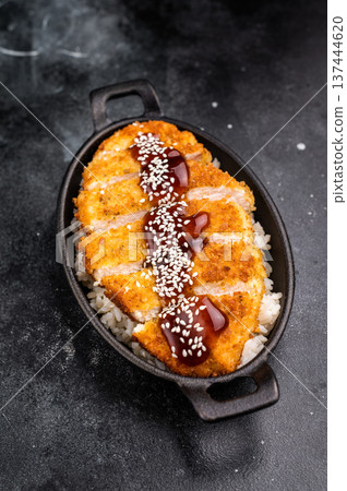 Crunchy Japanese cutlet katsu, seasoned to perfection and served with a side of rice and sauce. black background. top view Crunchy Japanese cutlet katsu, seasoned to perfection and served with a side of rice and sauce. black background. top view 137444620