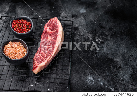 Raw beef picanha steak, featuring a thick layer of fat that adds flavor during cooking. black background. top view 137444626