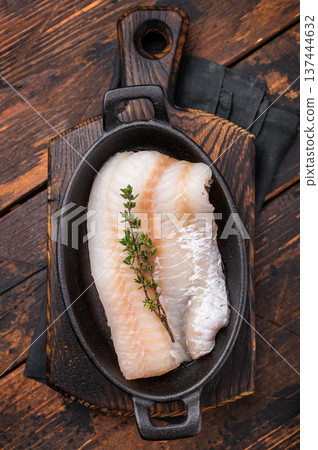 Pristine raw cod fillet, waiting to be marinated and cooked to perfection for a delightful dining experience. wooden background. top view 137444632