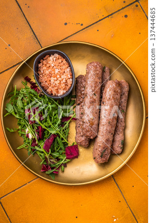 Grilled kofta or lula kebabs from mince lamb and beef meat on a plate with salad. brown background. top view Grilled kofta or lula kebabs from mince lamb and beef meat on a plate with salad. brown background. top view 137444685