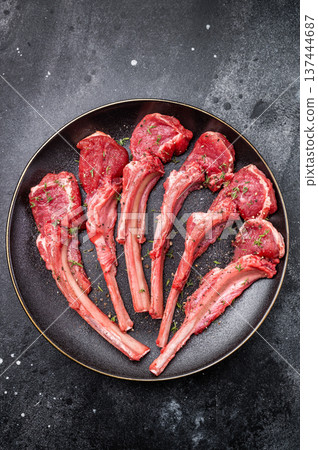 Fresh mutton chops, raw lamb meat cutlets on a plate. black background. top view Fresh mutton chops, raw lamb meat cutlets on a plate. black background. top view 137444687