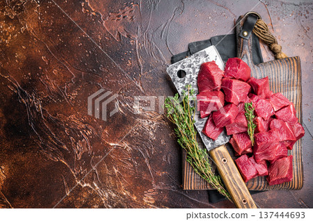 Diced Raw Boar meat, uncooked Game Meat on butcher cutting board. brown background. top view 137444693