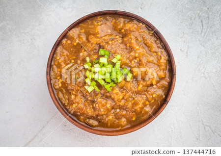 Traditional baigan bharta roasted eggplant aubergine mash served in rustic bowl on wooden board with lemon slices on light textured background top view 137444716