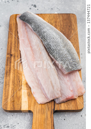 Raw sea bass or seabass fillets with thyme on rustic wooden cutting board, fresh Mediterranean seafood ingredient Raw sea bass or seabass fillets with thyme on rustic wooden cutting board, fresh Mediterranean seafood ingredient 137444721