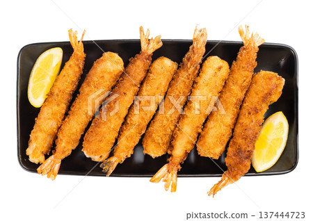 Crispy breaded shrimp tempura or ebi fry served with lemon on black plate, golden fried seafood appetizer isolated on white background, top view. 137444723