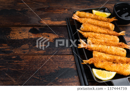 Golden deep fried prawns in panko breadcrumbs, ebifry style seafood appetizer shot from above, crispy asian cuisine finger food on wooden background. 137444739