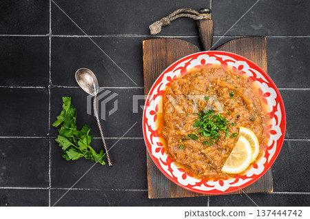 Classic Indian eggplant bharta vegetarian mashed aubergine curry dip served in decorative red plate with lemon garnish dark background food photography Classic Indian eggplant bharta vegetarian mashed aubergine curry dip served in decorative red plate with lemon garnish dark background food photography 137444742