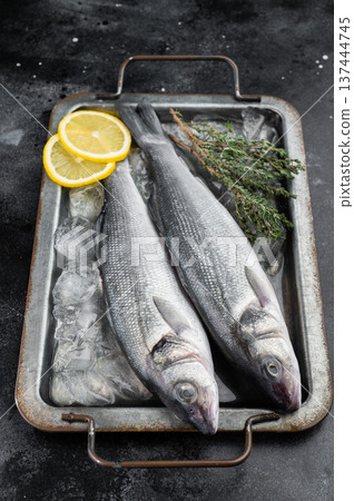 Fresh branzino or sea bass pair on crushed ice in metal tray, natural marine fish with citrus and herbs highlighting premium seafood quality and cold storage. Fresh branzino or sea bass pair on crushed ice in metal tray, natural marine fish with citrus and herbs highlighting premium seafood quality and cold storage. 137444745