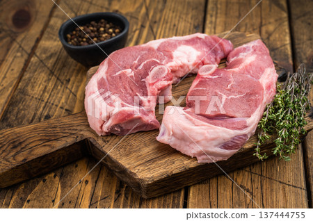 Fresh raw lamb chump cutlets from saddle section placed on wooden board with thyme seasoning, traditional butcher style composition for gourmet cooking. Fresh raw lamb chump cutlets from saddle section placed on wooden board with thyme seasoning, traditional butcher style composition for gourmet cooking. 137444755