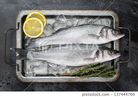 Chilled sea bass duo preserved on ice with fresh herbs and citrus, minimalistic culinary background suitable for menu design and retail seafood concept. 137444760