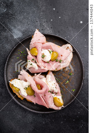Bruschetta with Prosciutto Cotto ham, burrata mozzarella and olives. black background. top view Bruschetta with Prosciutto Cotto ham, burrata mozzarella and olives. black background. top view 137444843