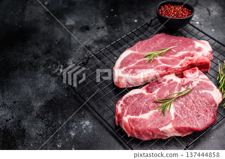 Raw pork tender steak, fresh neck meat with herbs on steel rack. black background. top view 137444858