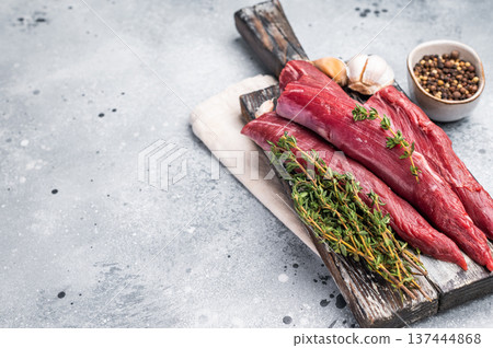 Raw lamb tenderloin fillet pieces, fresh mutton meat on wooden board. grey background. top view Raw lamb tenderloin fillet pieces, fresh mutton meat on wooden board. grey background. top view 137444868