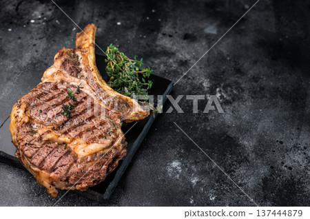 BBQ Grilled Tomahawk beef steak, cooked rib eye with bone on marble board. black background. top view BBQ Grilled Tomahawk beef steak, cooked rib eye with bone on marble board. black background. top view 137444879