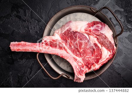 Raw tomahawk steak with marbling, fresh rib eye with bone. black background. top view 137444882