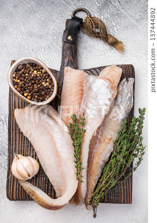fresh Raw Pollock fish fillets on a wooden board with herbs. white background. top view 137444892