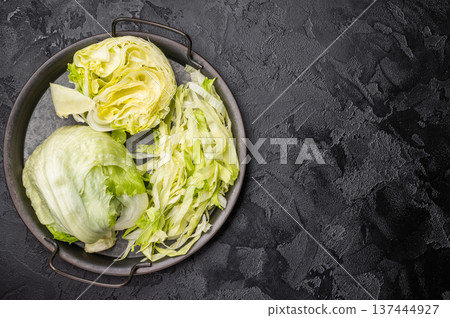 Fresh raw iceberg lettuce salad cut leaves. black background. top view Fresh raw iceberg lettuce salad cut leaves. black background. top view 137444927