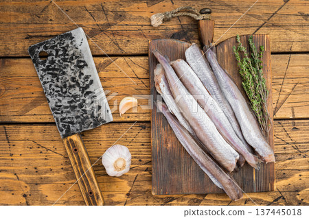 Uncooked silver blue whiting resembling pollock or whiting fillet styled with garlic and thyme on wooden table, natural ocean catch food photography Uncooked silver blue whiting resembling pollock or whiting fillet styled with garlic and thyme on wooden table, natural ocean catch food photography 137445018