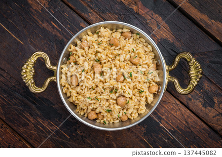 Traditional Turkish bulgur pilav nohutlu with chickpeas and thyme in metal bowl on dark wooden table overhead 137445082