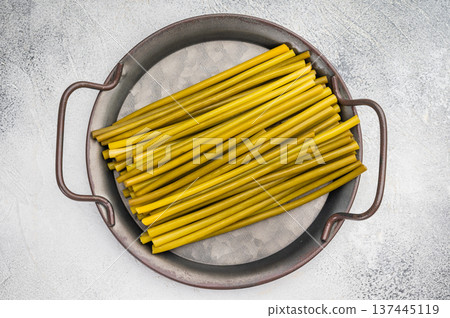 Fresh Fermented ramsons stems arranged in metal pan on light background. Wild garlic ingredient, foraged spring greens, minimal rustic food concept.. Fresh Fermented ramsons stems arranged in metal pan on light background. Wild garlic ingredient, foraged spring greens, minimal rustic food concept.. 137445119