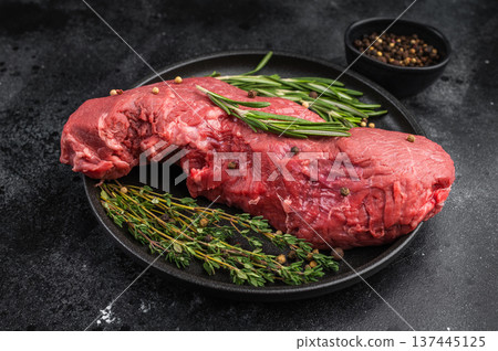 Raw beef tenderloin on black pan with rosemary thyme and pepper. Fresh premium meat ideal for roast beef roasting or fillet recipes. Raw beef tenderloin on black pan with rosemary thyme and pepper. Fresh premium meat ideal for roast beef roasting or fillet recipes. 137445125