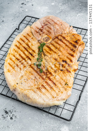 Grilled bone in pork shoulder with herbs on cooling rack cooked meat with grill marks prepared for barbecue and rustic serving Grilled bone in pork shoulder with herbs on cooling rack cooked meat with grill marks prepared for barbecue and rustic serving 137445131