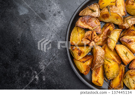 Crispy potatoes with skin seasoned with rosemary and garlic in pan. Homemade comfort food overhead view 137445134
