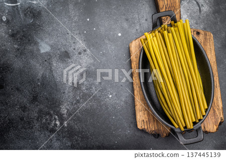 Pickled ramsons stems in cast iron cookware on wooden board dark food background natural plantbased ingredient Pickled ramsons stems in cast iron cookware on wooden board dark food background natural plantbased ingredient 137445139