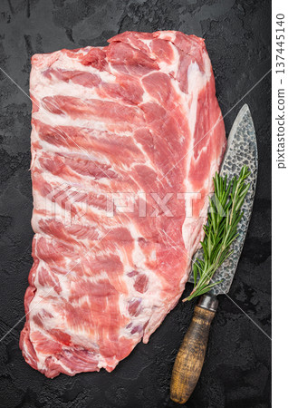 Fresh uncooked pork spareribs whole rack with rosemary and knife overhead view barbecue grilling and smoking ingredient 137445140