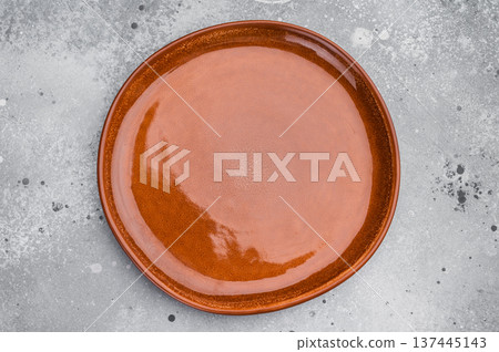 Empty brown ceramic plate top view isolated on background. Glossy round tableware with copy space 137445143