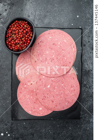 Smooth pink salam beef slices placed on a black slate board with vintage fork and pepper perfect for charcuterie and gourmet recipe visuals Smooth pink salam beef slices placed on a black slate board with vintage fork and pepper perfect for charcuterie and gourmet recipe visuals 137445146