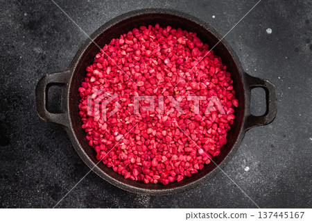 Sublimated raspberry granules with intense red color in cast iron pan. Natural ingredient flatlay with copy space 137445167