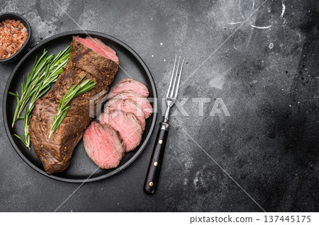 Medium rare roast beef cooked whole and sliced with rosemary. Juicy roasted beef tenderloin served in cast iron pan with copy space. Medium rare roast beef cooked whole and sliced with rosemary. Juicy roasted beef tenderloin served in cast iron pan with copy space. 137445175
