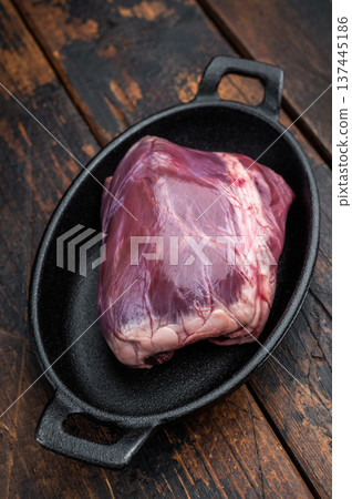 Raw heart used in pork cuisine placed on cast iron with thyme showing dense muscle fibers on rustic wood background. Raw heart used in pork cuisine placed on cast iron with thyme showing dense muscle fibers on rustic wood background. 137445186