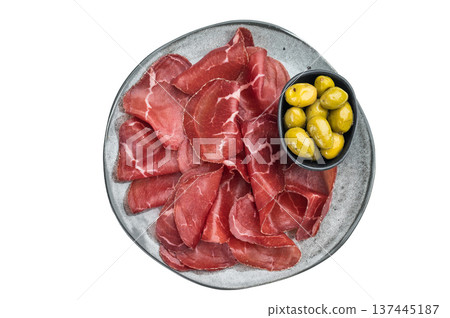 Italian Bresaola Air dried beef slices and marinated olives served on a textured gray plate, captured flat lay with minimal bright backdrop. Italian Bresaola Air dried beef slices and marinated olives served on a textured gray plate, captured flat lay with minimal bright backdrop. 137445187