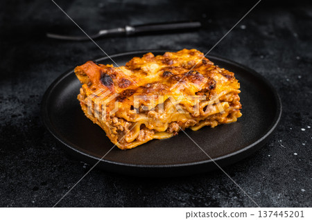 Traditional lasagne al forno with beef bolognese and baked cheese served on black plate top view Traditional lasagne al forno with beef bolognese and baked cheese served on black plate top view 137445201