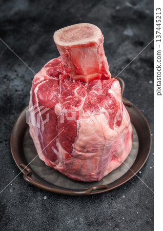 Raw veal shank hock whole piece with bone in cooking pan on stone background premium calf meat for braising and cuisine Raw veal shank hock whole piece with bone in cooking pan on stone background premium calf meat for braising and cuisine 137445213