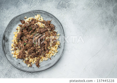 Turkish kavurma over pilaf showing browned fibers, maillard crust, collagen rich shredded meat and detailed macro texture on ceramic plate. Turkish kavurma over pilaf showing browned fibers, maillard crust, collagen rich shredded meat and detailed macro texture on ceramic plate. 137445228