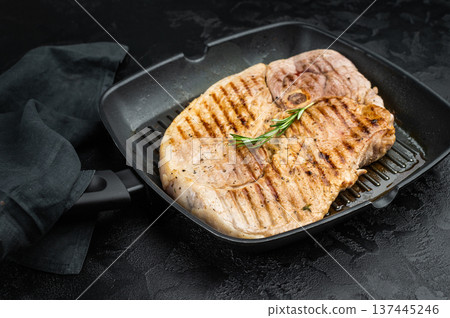 Grilled bone in pork shoulder in grill pan with rosemary on dark textured background juicy cooked meat with grill marks and copy space 137445246