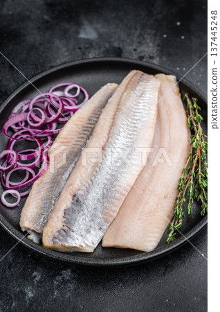 Salted herring fillets with red onion and thyme in cast iron pan. Dark stone background seafood appetizer with copy space. 137445248