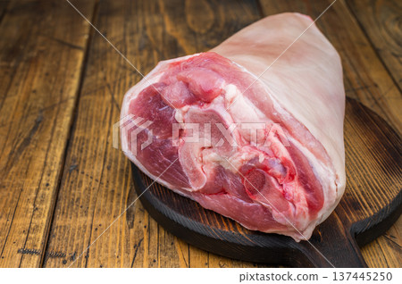 Raw pork knuckle hock with rind bone and muscle fibers on rustic board with thyme salt and meat fork ideal for butchery prep and culinary detailing. 137445250