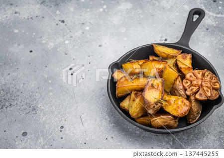Baked potato wedges seasoned with rosemary and garlic in skillet. Simple healthy side dish with copy space 137445255