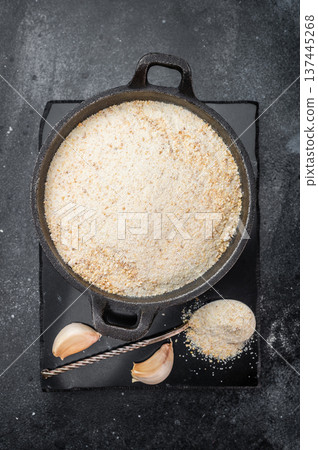 Dried granulated garlic seasoning with fine texture in skillet. Culinary ingredient flatlay on dark background 137445268